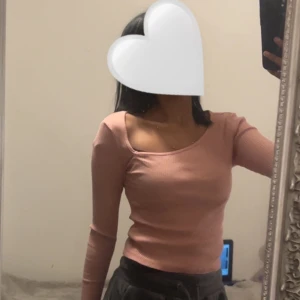 Rosa ribbad topp - Säljer en söt rosa ribbad topp med långärmad design. Toppen har en tight passform och en rundad halsringning, perfekt för en stilren look.