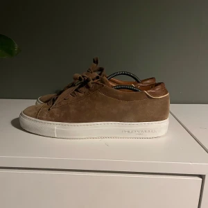 Bruna sneakers från Philippe Model - Snygga bruna sneakers i mocka från Philippe Model. Skorna har en vit sula och snörning framtill. Perfekta för en stilren look. Går för 2500kr nya men säljer de för 800kr