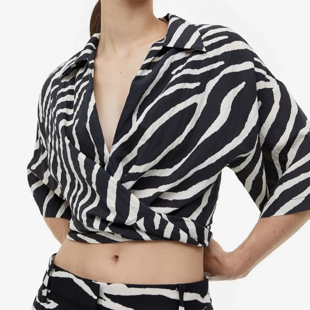 Snygg zebramönstrad blus med knyt framtill. Perfekt för en trendig look. Blusen har korta ärmar och en klassisk krage.. Paidat.