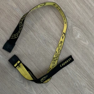 Svart och gult bälte från Capeesh - Coolt bälte från Capeesh i svart och gult, väldigt limiterat säljes ej längre. Riktigt bra skick. Unika mönster, Perfekt för att ge din outfit en clean touch. Bältet har en modern design med ett spänne i plast och magnet.