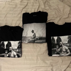 Svart t-shirt med tryck - Svart t-shirt med ett stort svartvitt tryck på framsidan som visar en person som röker. T-shirten har en normal passform och korta ärmar. Perfekt för en avslappnad stil.