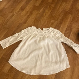 Vit spetsblus från kapphal - Säljer en söt vit blus från Jippah med vackra spetsdetaljer på ärmarna och övre delen. Blusen har långa ärmar och en luftig passform, perfekt för en stilren look. Passar bra till både jeans och kjol. 🌸