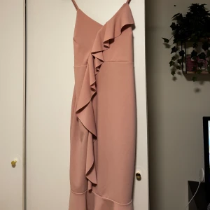 Rosa klänning från Boohoo - Säljer en söt rosa klänning från Boohoo med volangdetaljer. Klänningen är perfekt för sommaren. Den är gjord i ett stretchigt material som ger en bekväm passform.