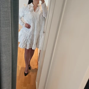 Vit klänning med volanger - Säljer en söt vit klänning frå H&M med volanger och långärmad design. Klänningen har ett diskret mönster och en luftig passform som ger en romantisk känsla. Perfekt för vår och sommar!