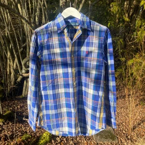 Flannelskjorta Ralph Lauren - Snygg blå gul rutig skjorta från Ralph Lauren i storlek S. Skjortan har långa ärmar och klassiska knappar framtill. Den är tillverkad i bomull och har en broderad logga på bröstet. Perfekt för en stilren look!