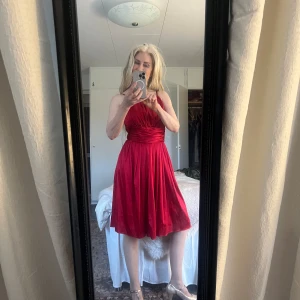 Röd klänning från Your Sixth Sense - Snygg röd klänning från Your Sixth Sense med axelbandslös design och vackra draperingar. Perfekt för en elegant kväll. Klänningen har en dragkedja i ryggen för enkel påklädning.