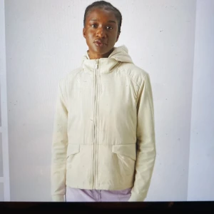 LIEZEN Jacket  - Säljer en LIEZEN beige jacka med huva och dragkedja framtill. Jackan har långa ärmar och praktiska fickor. Perfekt för kyligare dagar när man spelar golf. Fickor med lock. Huva kan tas av. Den är köpt från Daily Sports born in Sweden. 