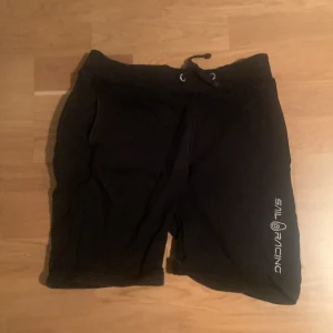 Svarta shorts från Sail Racing - Snygga svarta shorts från Sail Racing med snörning i midjan. Perfekta för en avslappnad stil. Logotypen är tryckt på benet för en sportig look. Storleken är för dig som är ca 170 cm, och shortsen kan omvandlas till storlek S.