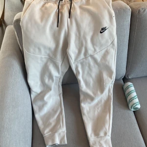 Vita mjukisbyxor från Nike - Säljer ett par vita mjukisbyxor från Nike med svart dragsko i midjan och Nike-logga på benet. Byxorna har en avslappnad passform och är perfekta för en chill dag hemma eller en snabb tur till affären.