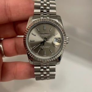 Seikomod 36mm - Säljer seikomod (grey datejust 36mm).  - NH35 urverk. - Reptåligt safirglas. - 41 timmars gångreserv. - Vattentät. - 36mm diameter. - Öppen baksida. - Jubilee länk med hidden clasp. - Ljus blå lume (för att se i mörker).  Levereras i låda med utrustning för att justera länk. Köpt för 3600