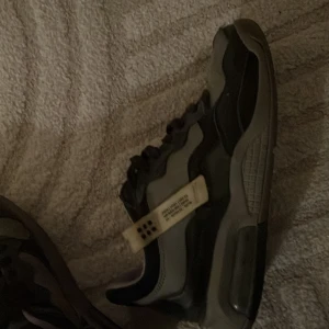 Svarta och grå sneakers med detaljer - Snygga sneakers i svart och grått med en unik design. Skorna har en robust sula och snörning för en säker passform. Perfekta för en stilren look.