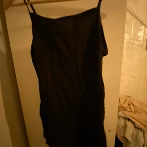 Svart axelbandslös klänning - Snygg svart klänning med smala axelband. Perfekt för en stilren look. Klänningen har en enkel design som gör den lätt att matcha med olika accessoarer.