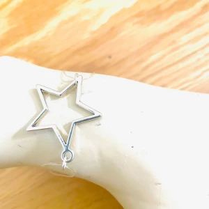 By prisförslag- Silverfärgat stjärnarmband - Snyggt armband med en stjärnformad berlock i silverfärg. Armbandet har en tunn kedja som ger ett elegant och minimalistiskt intryck. Perfekt för att lägga till en subtil touch av stil till din outfit.