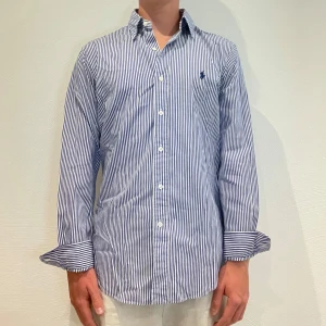 Randig Ralph Lauren skjorta  - Vit/ blå randig Ralph lauren skjorta || Storlek M (Slim Fit) || Skjortan är i bra skick || Mitt pris 599kr || Modellen på bilden är 170cm och väger 62kg || Tveka inte på att höra av dig vid frågor eller funderingar 