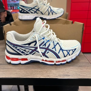 AsicsGel-Kayano 20 Cream / Deep Marine - Snygga ASICS Gel-Kayano 20 sneakers i vitt mesh med blå och röda detaljer. Jag köpte dem tillsammans med ett par andra som jag använda och då sa de i kassan att dessa också såg använda ut men har inte använt dessa så säljer dem. Kvitto finns 