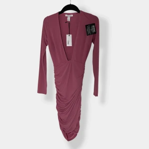 Rosa klänning från NLY Design - Supersnygg långklänning i dämpad rosa från NLY Design. Djup v-ringning, långa ärmar och draperad kjol som ger en snygg och elegant look. Tillverkad i mjukt, stretchigt material som sitter perfekt på kroppen.