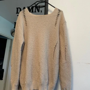 Beige stickad tröja  - Beige stickad tröja med coola håldetaljer längs axlar och ärmar.  Helt Nytt