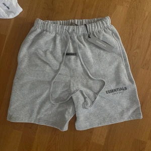 Essentials shorts - Bekväma och stilrena shorts från märket Essentials. Designade med en minimalistisk estetik och tillverkade av en mjuk bomullsblandning som ger en skön passform. Perfekta för vardagsbruk, träning eller en avslappnad dag på stan. Resår i midjan med dragsko för justerbar komfort.