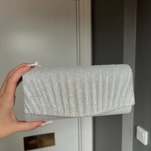 Glittrig silver kuvertväska med kedja - Snygg kuvertväska i silver med glitter endast använd en gång 