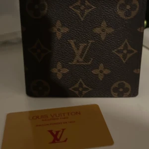 Monogram Plånbok - Säljer en klassisk plånbok i brunt skinn med ikoniskt monogrammönster. Plånboken har flera kortfack och ett myntfack på insidan. Perfekt accessoar för dig som gillar lyxiga detaljer och tidlös design.