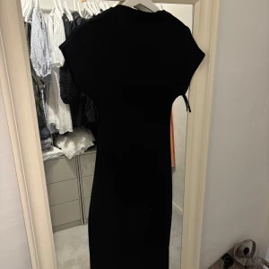 Svart långklänning med kort ärm - En svart långklänning med korta ärmar och rak passform. Klänningen har en enkel design utan synliga detaljer eller mönster. Bra skick knappt använd. 