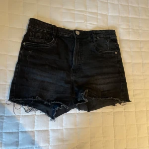 Svarta jeansshorts med fransig kant - Snygga svarta jeansshorts med rå, fransig kant och klassisk femficksdesign. Shortsen har en mörk tvätt och en lite tajt passform, Passar grymt till sneakers eller bara tofflor. Shortsen är från en av Lindex kollektioner. 
