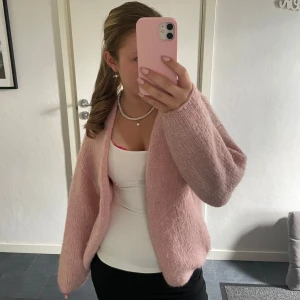 Ljusrosa stickad kofta från Lindex - Supermysig ljusrosa stickad kofta från Lindex i oversized modell. Koftan är öppen framtill och har breda ärmar för en chill vibe. Perfekt att slänga över en topp för en söt och avslappnad look. Storleken är XS men passar även dig som bär S.🩷🩷🩷