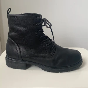 Svarta boots från Vagabond i skinn - Stilrena svarta boots från Vagabond i äkta skinn med snörning och dragkedja på sidan. Grov sula för extra grepp och rund tå. Perfekta för dig som gillar en klassisk look med edge.