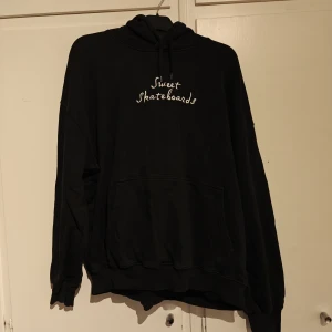 Svart hoodie från Sweet Skateboards - Svart oversized hoodie från Sweet Skateboards med vit broderad text på bröstet. Klassisk känguruficka framtill, huva med snörning och mjukt material. Perfekt för chill dagar eller skateparken.