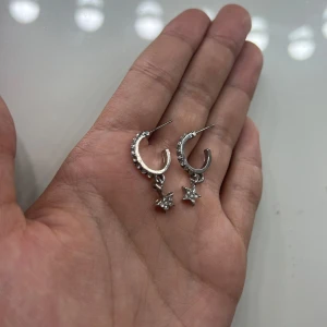 Silvriga örhängen med stjärnhänge - Snygga silvriga örhängen utan pluppar med små gnistrande stenar och hängande stjärnor. 