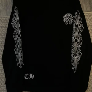 Svart Chrome Hearts långärmad tröja M - Säljer en svart långärmad tröja från Chrome Hearts i storlek M. Tröjan har vita tryck längs ärmarna och stort Chrome Hearts Los Angeles-tryck på ryggen. Snygg streetwear-vibe med unika detaljer och klassisk logga framtill.