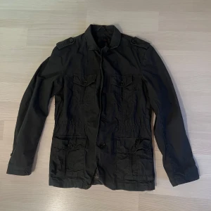 Svart parkajacka från Reserved - Svart jacka från Reserved med fyra stora fickor framtill, axelklaffar och knäppning med knappar. Jackan är i storlek S men passar som M, nypris 749 kr, mitt 250 kr 