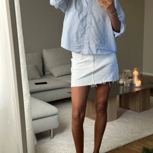 Vit jeanskjol från Perfect Jeans - Vit kort jeanskjol från Perfect Jeans i klassisk denim med rå kant nertill. Kjolen har en enkel design med fickor och knapp framtill. 🤍