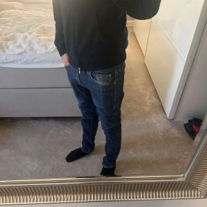 Tiger of Sweden jeans - Snygga mörkblå jeans från Tiger of Sweden med klassisk femficksdesign och raka ben. Jeansen har orangea kontrastsömmar och är tillverkade i ett slitstarkt bomullstyg. Perfekta för dig som gillar stilrena och tidlösa jeans. Personen på bilden är 177cm! Köpta för 999kr!