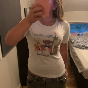 Vit t-shirt med parfymtryck  - Vit t-shirt med coolt tryck av parfymflaskor och texten 'Top Grade' framtill. 