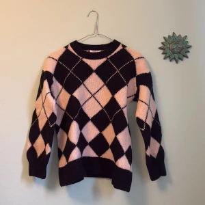 Svart och beige rutig stickad tröja XS - 100% ull. Snygg stickad tröja från & Other Stories i svart och beige med rutigt argylemönster. Tröjan har rund hals, ribbade muddar och lång ärm. Perfekt för dig som vill ha en trendig och mysig look under kyliga dagar.