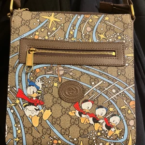Gucci x Disney axelväska med Kalle Anka - Säljer nu min Gucci och Disney collab väska då den inte används längre den är i väldigt bra och fint skick har bara använt den under några speciella tillfällen riktigt fin väska till någon som vill synas