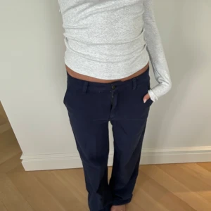 Mörkblå byxor med text på bakfickan - Säljer ett par mörkblå jeans. På bakfickan finns en vit broderad text.