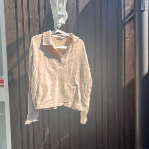 Beige pikétröja från Zara - Säljer en stilren beige pikétröja från Zara i storlek M. Tröjan har klassisk krage, knäppning med två knappar och är tillverkad i mjuk bomull. Perfekt för dig som gillar en clean och avslappnad look.