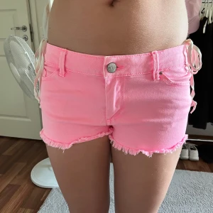 Rosa jeansshorts - Säljer ett par ljusrosa, tighta jeansshorts med fransig kant nedtill. Klassisk femficksmodell med knapp och dragkedja framtill. Lågmidjade med ch har storlek 36 men passar nog även 38!!❤️🥰 Säljer då de är lite för stora😔😔