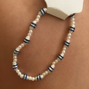 fotarmband med vita pärlor och blå glittriga detaljer - Ett söt fotarmband med vita pärlor och blå glittriga ringar mellan pärlorna. 