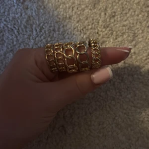 Chunky guldfärgade ringar i kedjemönster - Säljer flera chunky ringar i guldfärg med coolt kedjemönster. Perfekta för att ge din look lite extra edge och bling. Passar snyggt ihop eller var för sig för en trendig vibe. 10kr st. OBS!!! KOMMER GÖRAS RENT INNAN SICKAD