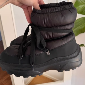 Svarta moon boots med snörning - Svarta moon boots med tjock sula och snörning. Skorna har en vadderad, puffig design och är perfekta för kalla dagar. Skorna är från hm och är använd två gånger och är i i superbra skick!