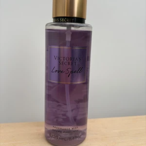 Victoria's Secret Love Spell mist - Fräsch och söt body mist från Victoria's Secret i doften Love Spell. Kommer i en genomskinlig plastflaska med lila vätska och guldfärgat lock. Doften har inslag av körsbärsblom och persika. Flaskan rymmer 250 ml och är perfekt att spraya på sig för en fruktig och blommig känsla.