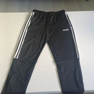 Svarta Adidas träningsbyxor strl 164 - Svarta träningsbyxor från Adidas som är sparsamt använd eftersom jag har flera par, men dessa är i jättebra skick.