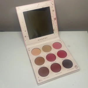 Ögonskuggspalett från Morphe - Säljer Morphe 9X Li'l Extra ögonskuggspalett med 9 nyanser i varma och bäriga toner. Paletten innehåller både matta och skimriga skuggor i nude, guld, rosa, rött och brunt. Perfekt för att skapa allt från enkla till riktigt dramatiska looks. Snygg rosa förpackning med spegel. Endast använd ett par gånger.