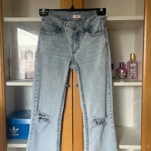 Ljusblå bootcut jeans från Nelly - Ljusblå jeans från Nelly med bootcut passform och slitna hål vid knäna och med snygga rosa broderade detaljer på bakfickorna💓dom är i nyskick knappt använda🌸