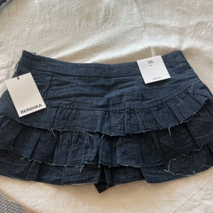 Mörkblå volangkjol från Bershka - Supersöt mörkblå kortkjol från Bershka med flera lager volanger och är helt nya (prislapp kvar). 