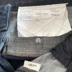 Filippa K Gwen Raw Denim Shorts M - Snygga mörkblå denimshorts från Filippa K i modellen Gwen Raw Denim Shorts. Klassisk femficksdesign med raka ben och hög midja. Tillverkade i jeansmaterial med stilrena sömmar och knappar bak. Perfekta för en clean och avslappnad look.