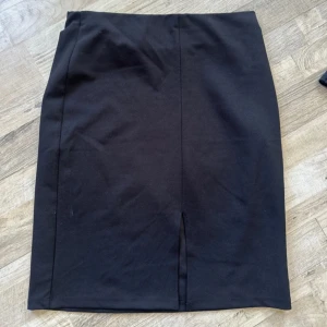 Svart pennkjol med slits - En klassisk svart pennkjol med slits framtill. Kjolen har en rak och stilren passform som sitter snyggt i midjan. Perfekt för dig som gillar en enkel men elegant look. Passar till både sneakers och boots.